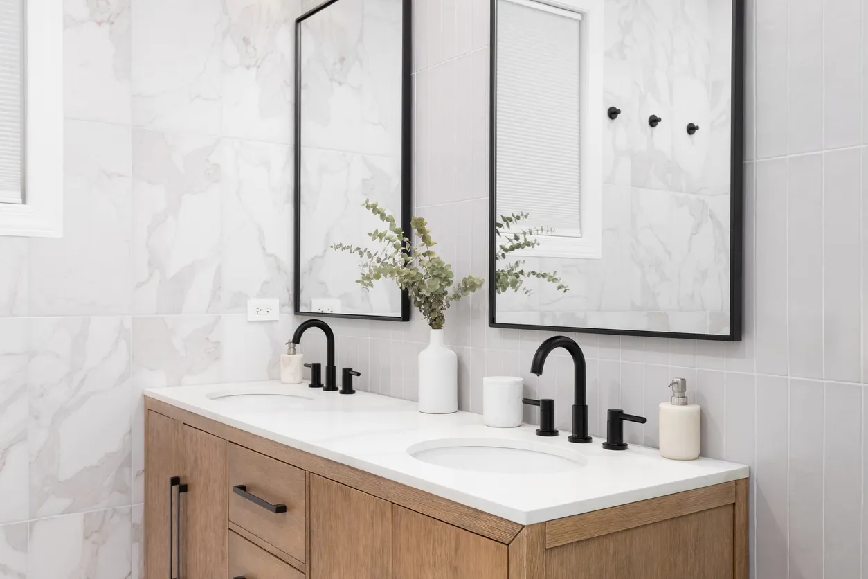 Detalle de baño con mueble de roble blanco y grifería negra.