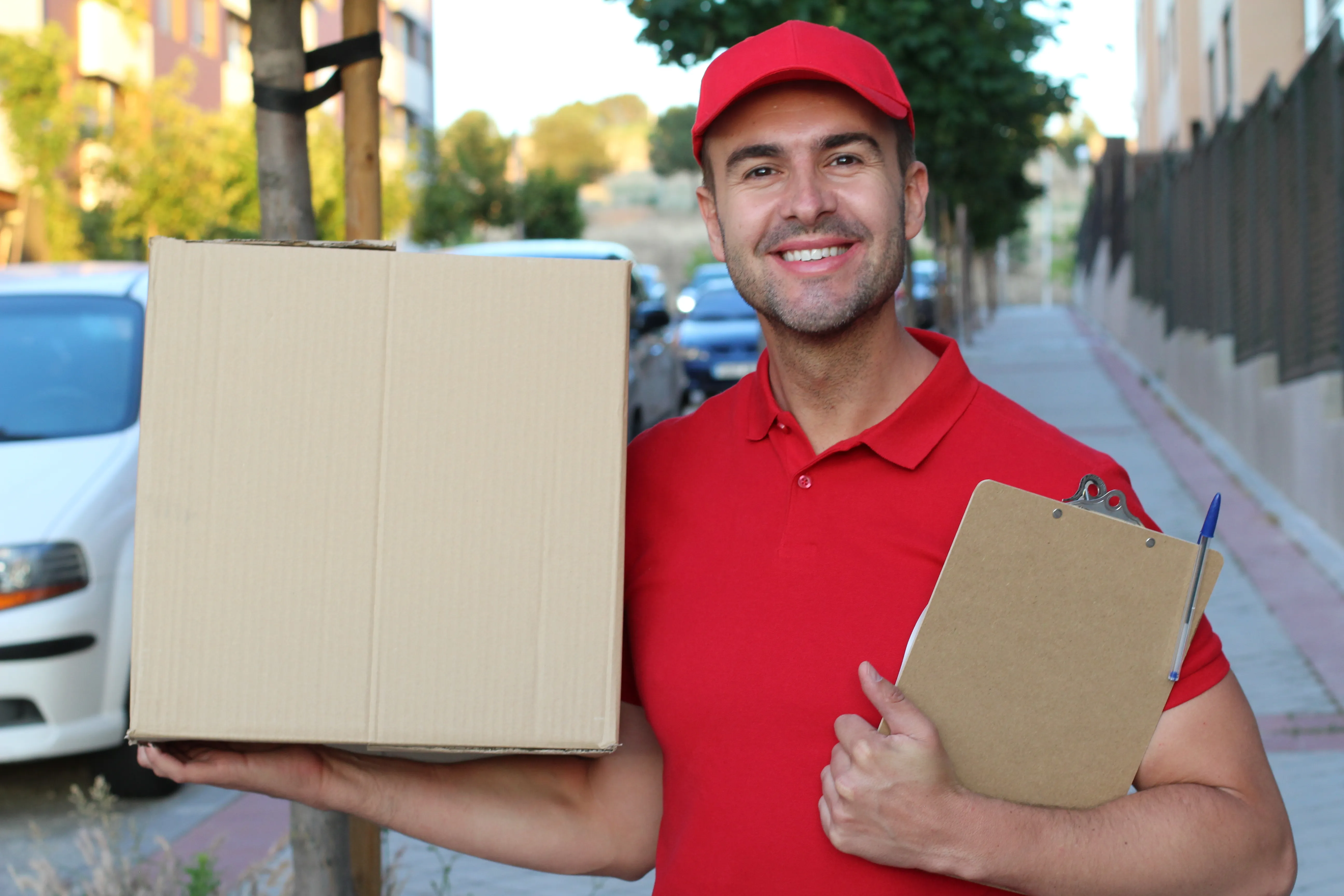 Delivery man holding a box outdoors with corporate uniform