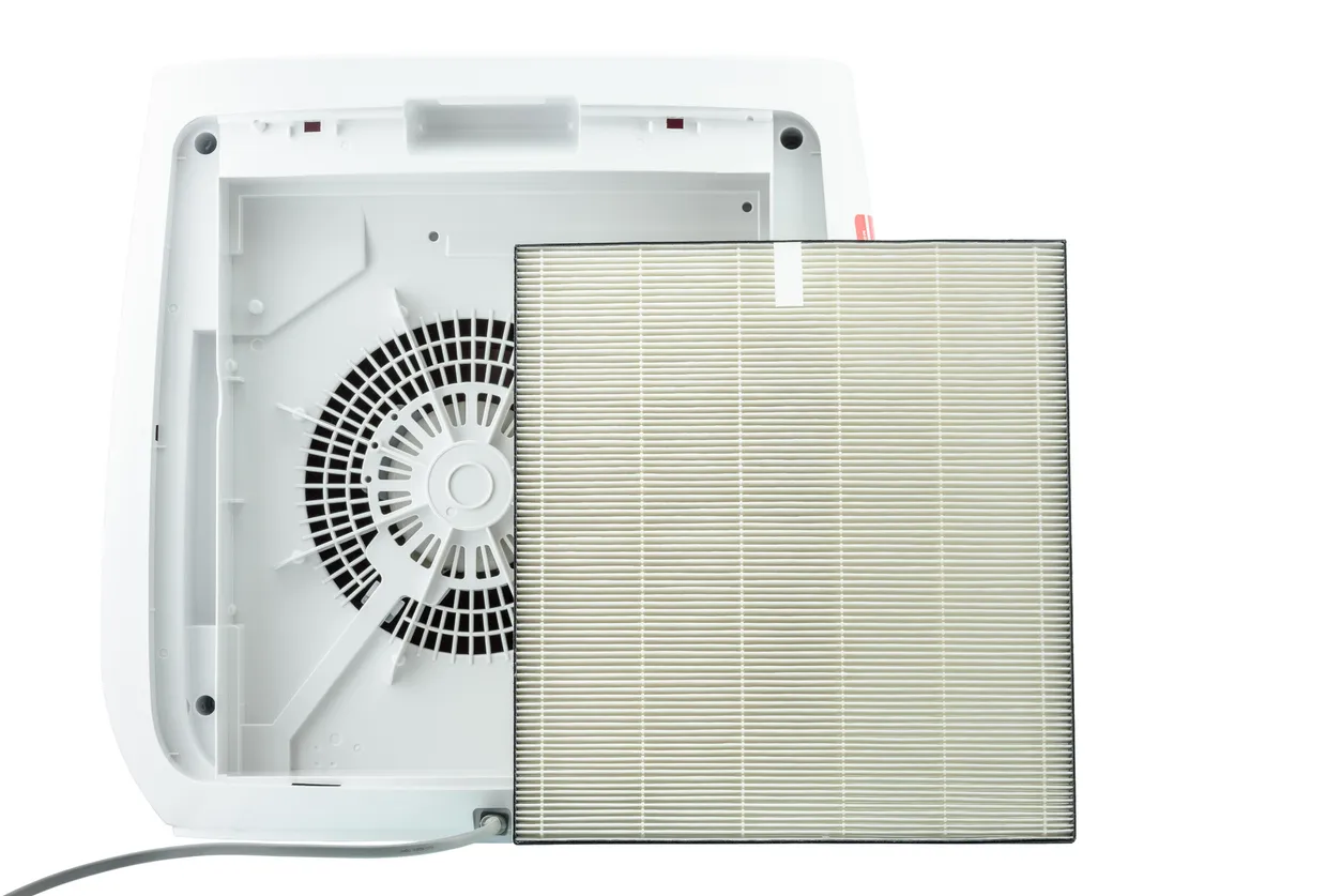 Vista trasera del ventilador de un purificador de aire con filtro HEPA de repuesto, aislado sobre fondo blanco.