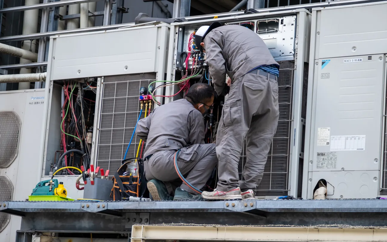 Ingenieros  arreglando una unidad de aire acondicionado en un edificio