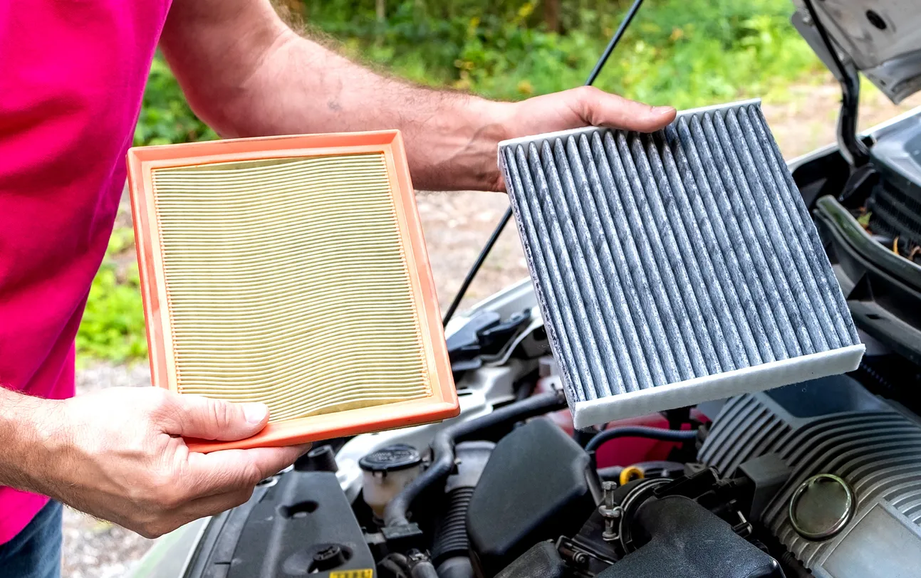 Cambio del filtro de aire de un coche. Un hombre sostiene un filtro de aire