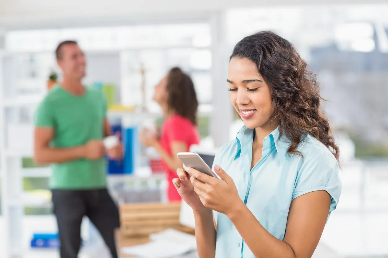 Empresaria creativa enviando mensajes de texto en un celular de media gama