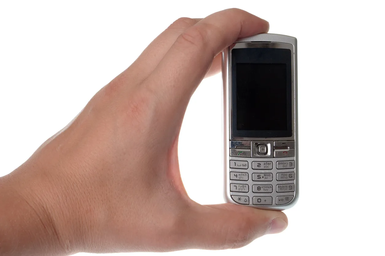 Celular cacahuatito color gris mostrado por una mano