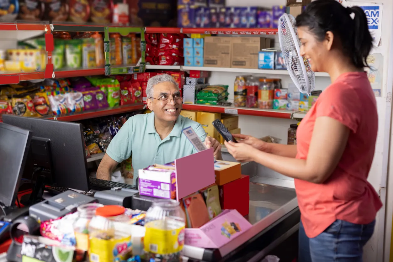 Mujer pagando mediante se celular en tienda de abarrotes. Un celular barato hace que todos tengamos acceso a la tecnología.