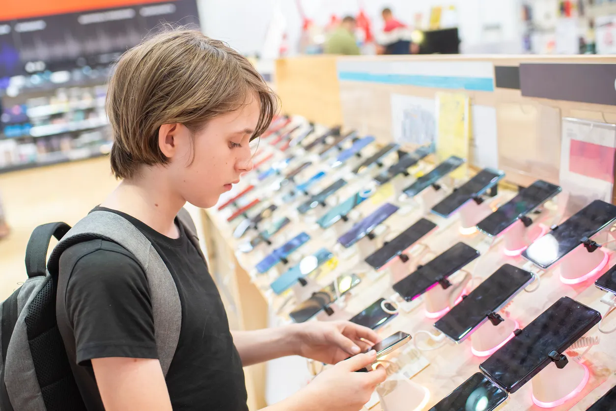 Joven revisando celulares en gran tienda de celulares. Estas tiendas son una gran oportunidad de negocio.
