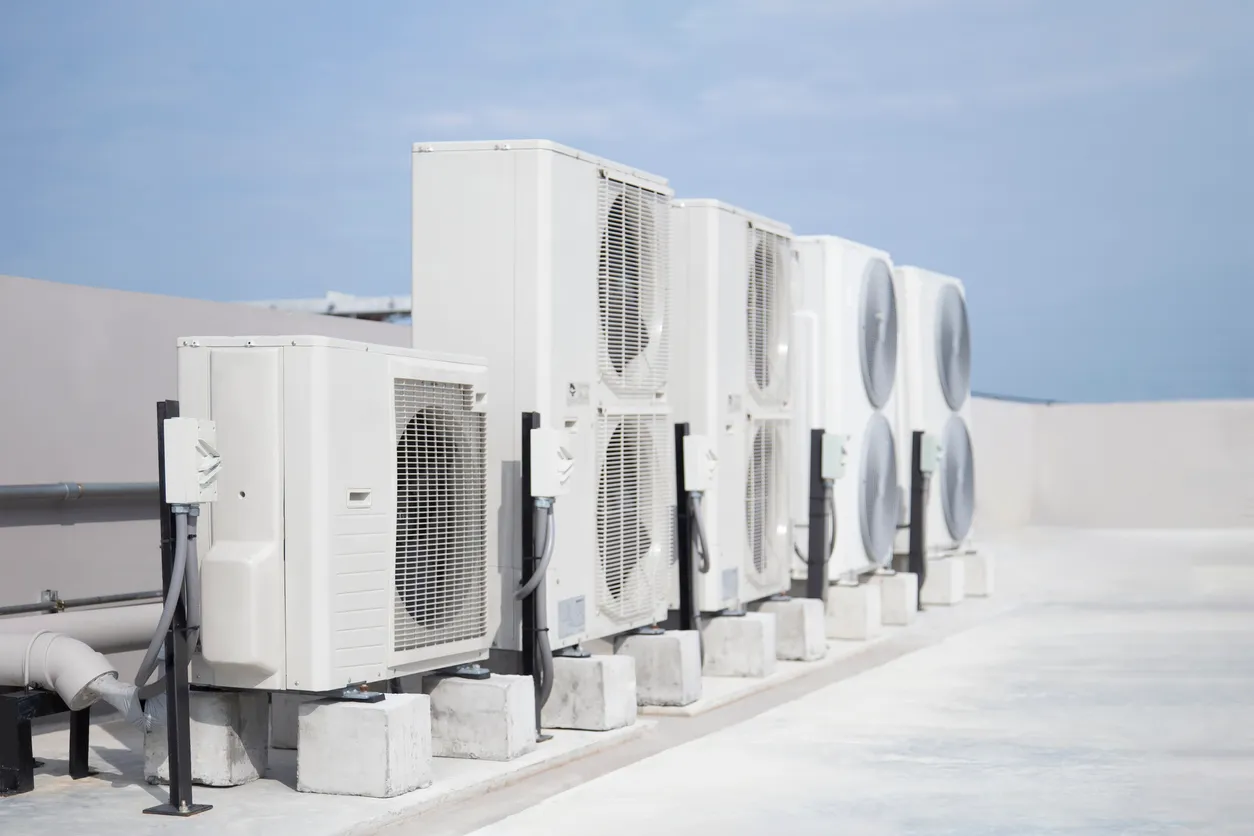 Aire acondicionado (HVAC) en el tejado de un edificio industrial con cielo azul y nubes.