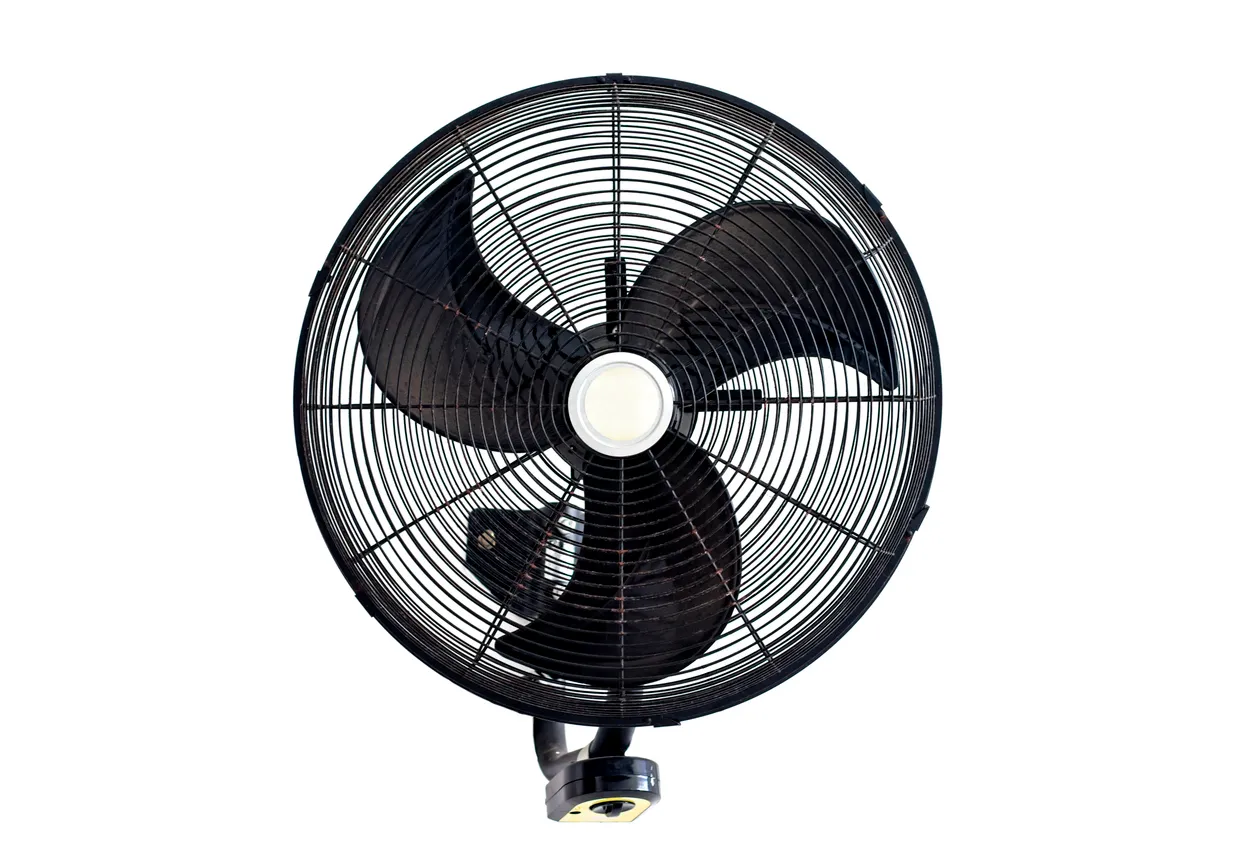 Antiguo ventilador negro con tres hélices y red de seguridad colgado en una pared blanca