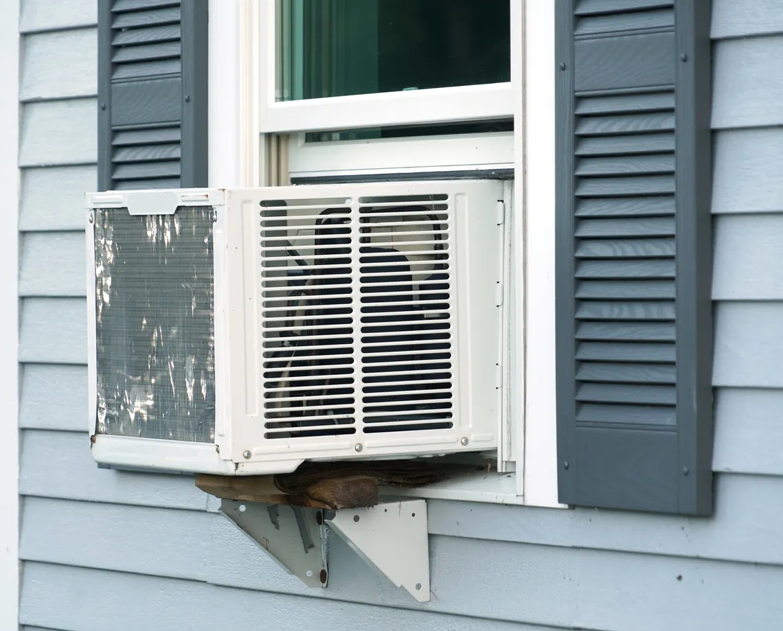 Aire acondicionado antiguo instalado en la ventana de una casa rústica