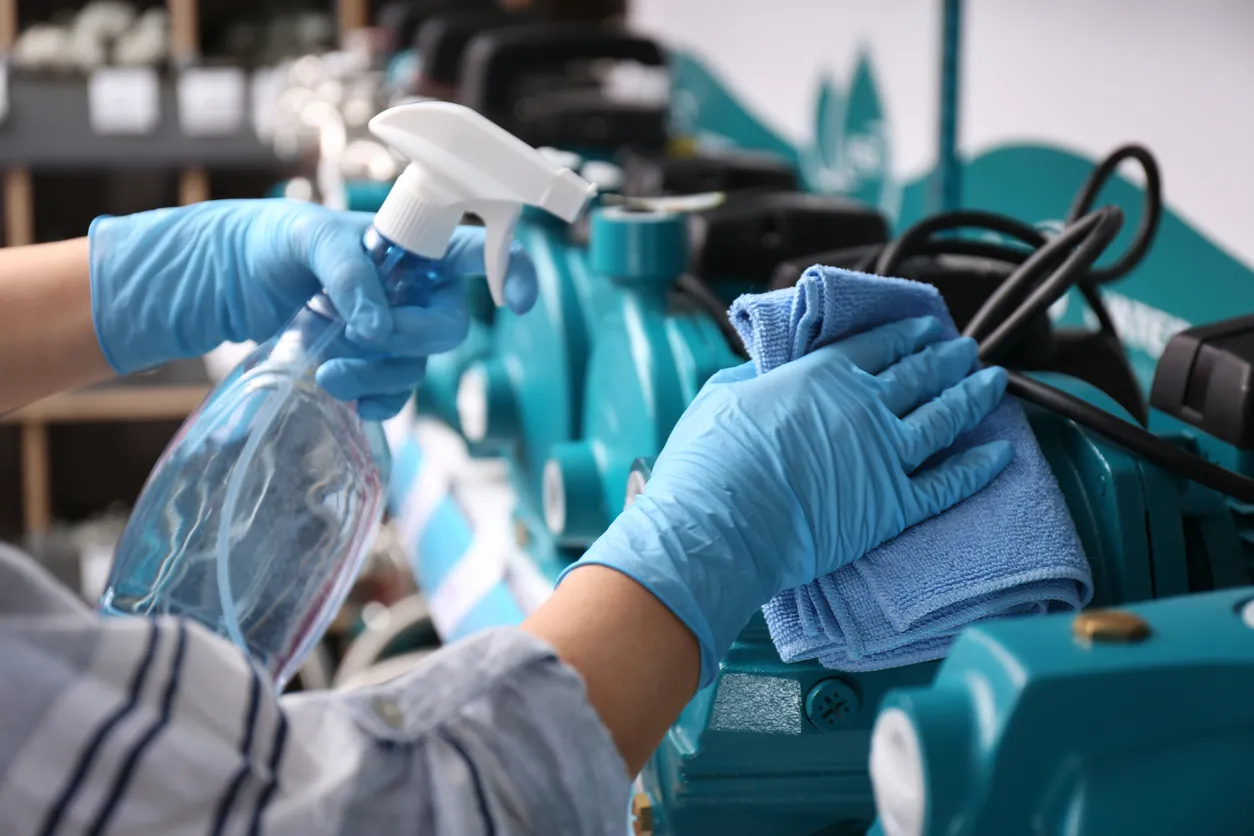 Woman cleaning water pump with rag and detergent in bathroom fixtures store