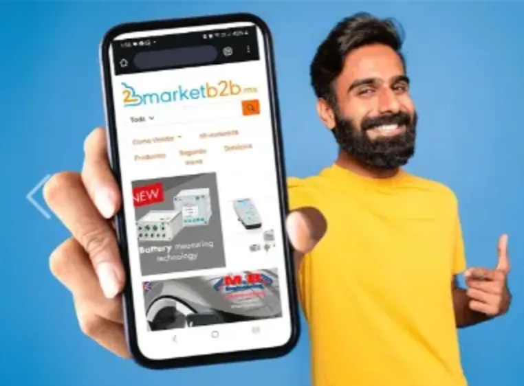 Joven con barba y sonrisa enseñando que en su celular tiene el catálogo de Market B2b, con su dedo esta haciendo un ademán 