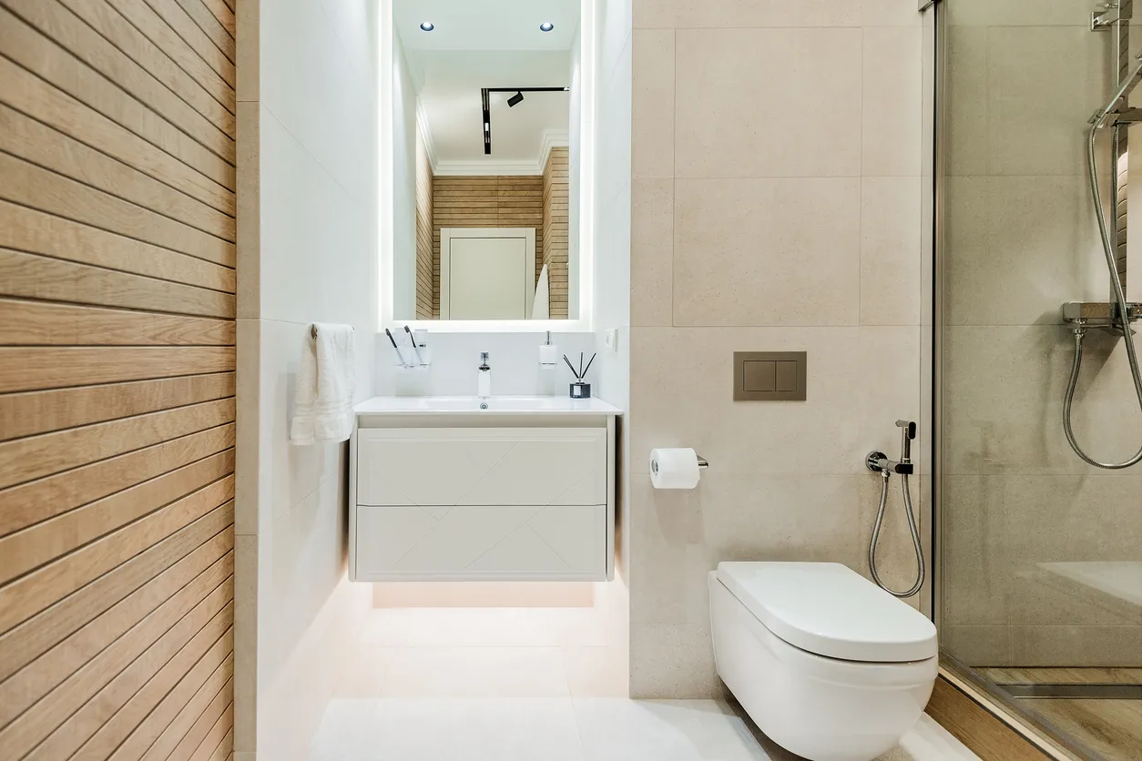 Interior de baño moderno con cabina de ducha de cristal e inodoro y lavabo blancos.
