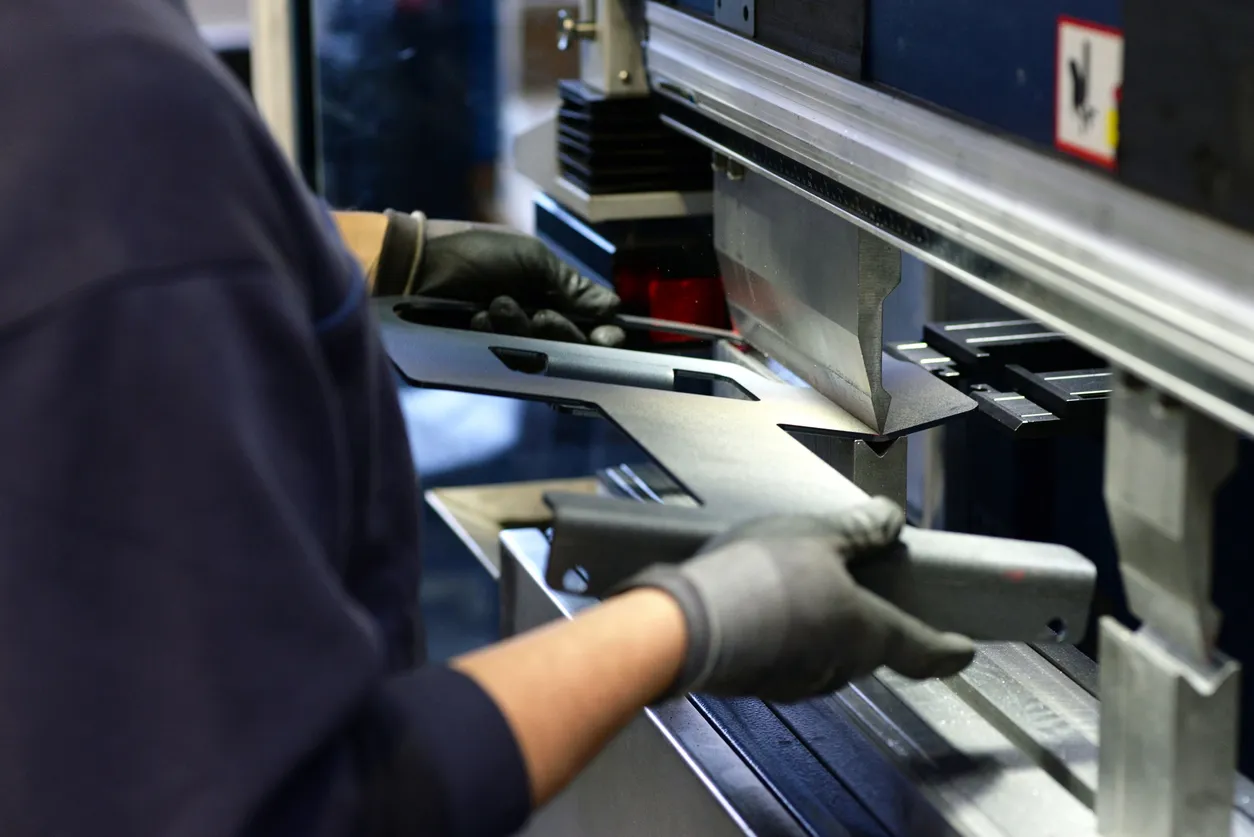 Un empleado opera una máquina dobladora en una empresa metalúrgica: dobla chapas metálicas para su posterior procesamiento.