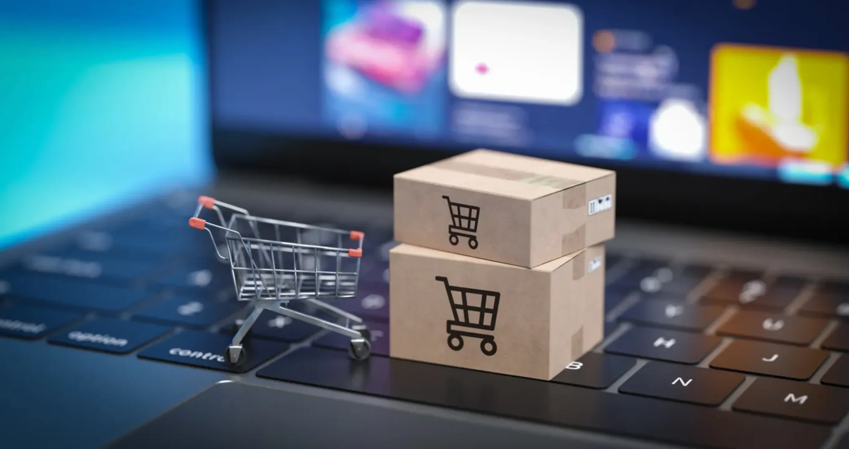 Carrito de compra y cajas de cartón encima de una computadora