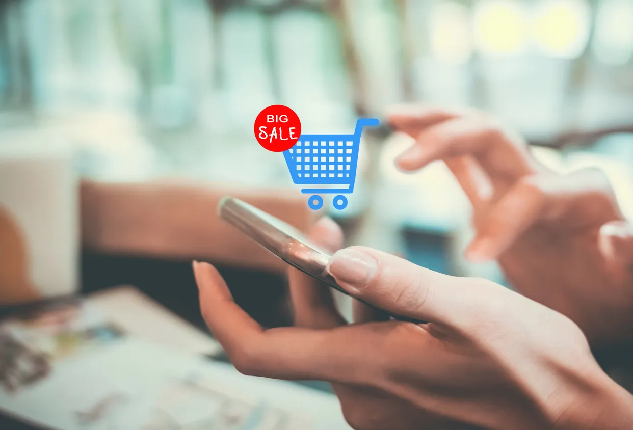Mano de una persona dando push en un celular y un carrtiro de supermercado, representando la compra en linea.