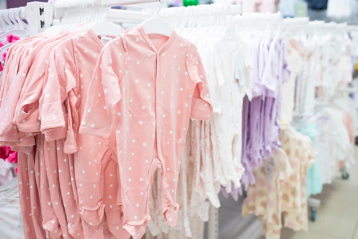 Ropa de bebé niña colgada en perchas en una tienda de ropa de bebé mayoreo