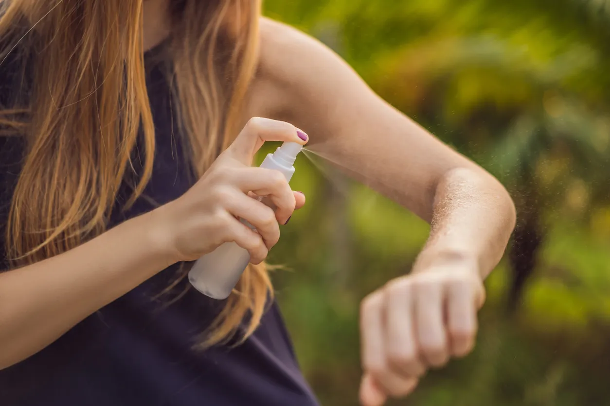 Joven mujer roseandose repelente de mosquitos en su brazo.