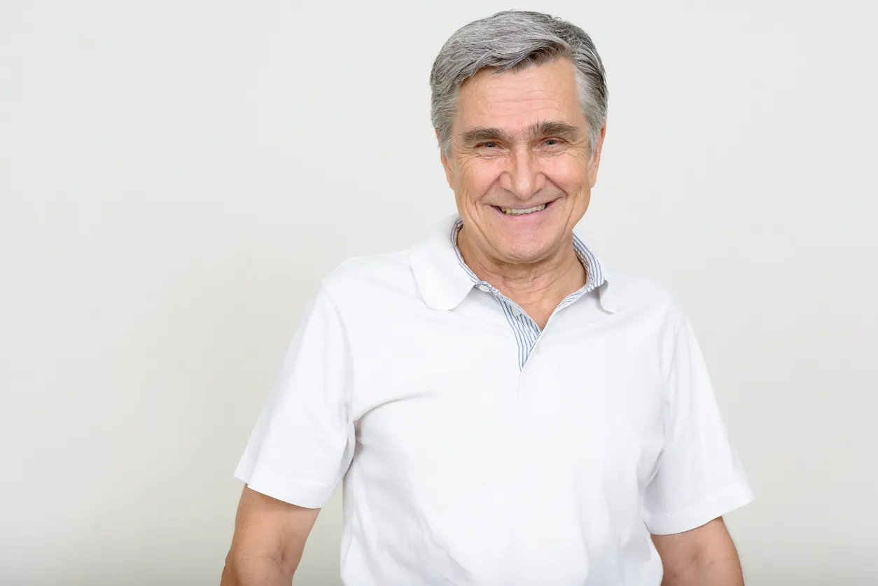 Hombre mayor de 50 años con playera tipo polo blanca con gris claro