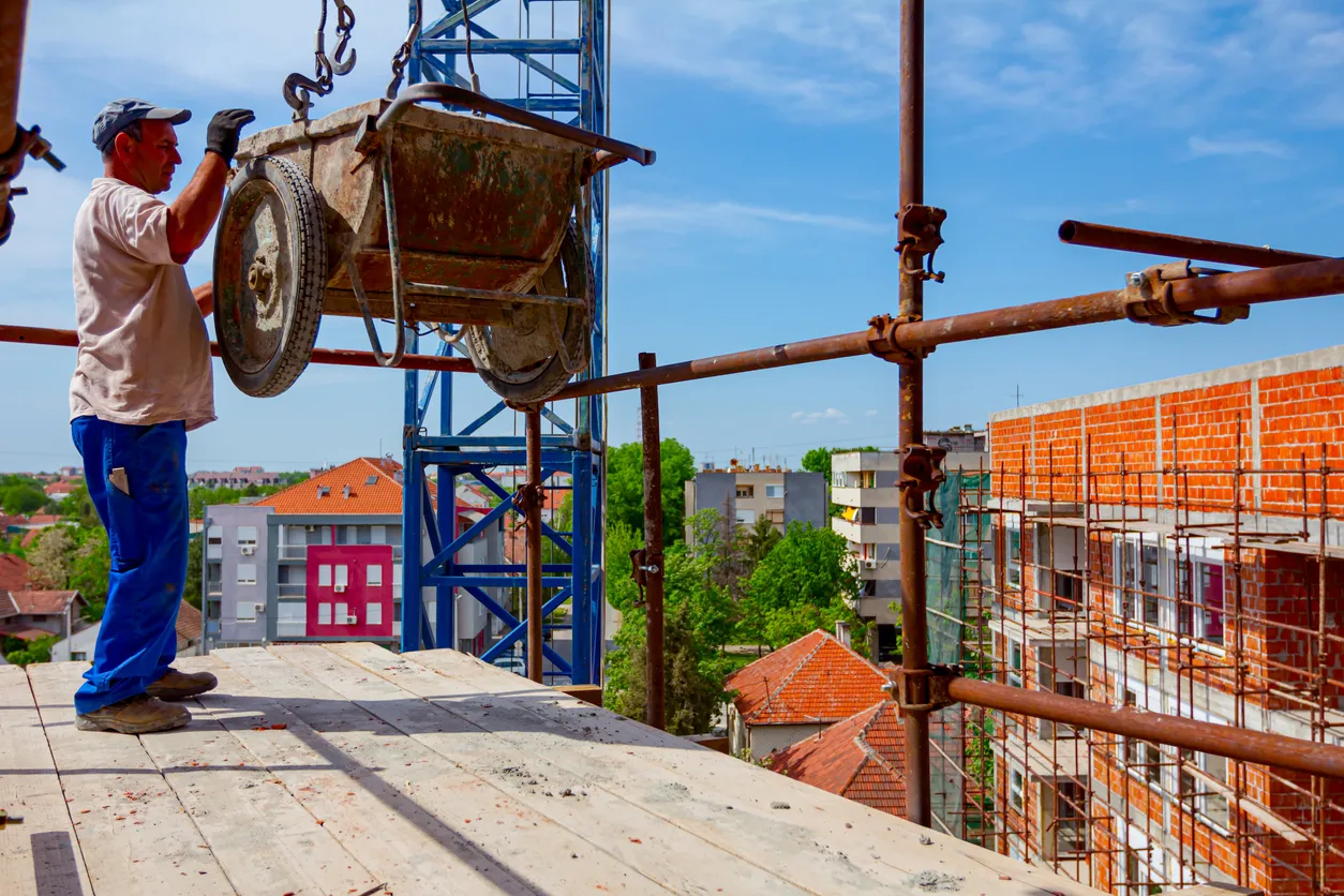 Trabajador revisando el levantamiento de un equio con material con un malacate