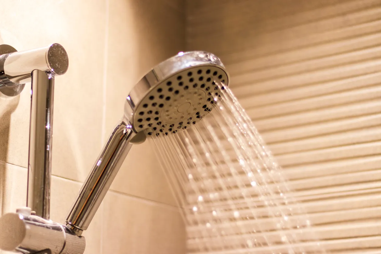Regadera de un baño abierta virtiendo agua. La zeolita ayuda a disminuir la dureza del agua,