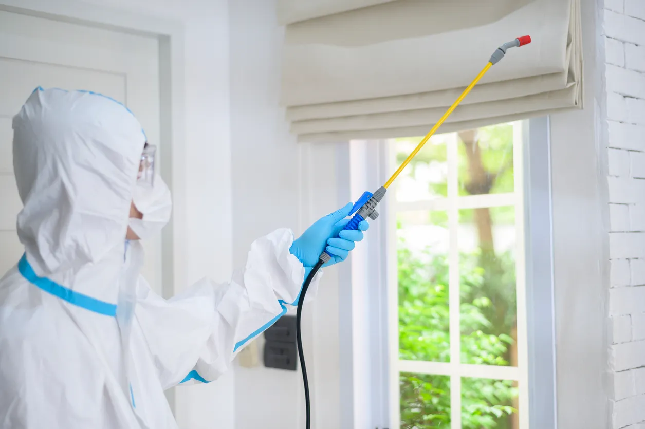 Persona realizando la sanitización de la habitación de una casa