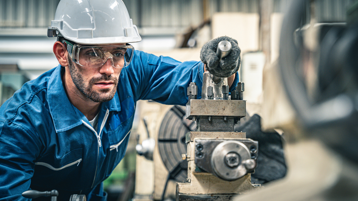 Ingeniero varón que opera la máquina de torno.