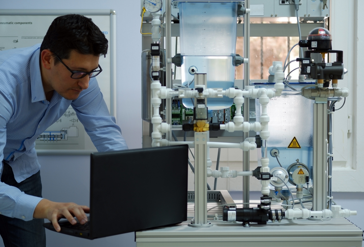 Concéntrese en el ingeniero que está programando PLC con portátil para un kit de proceso analógico