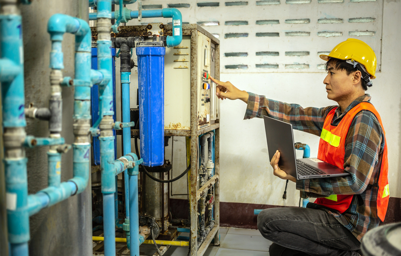 Ingeniero que trabaja en la fábrica de agua potable utilizando una tableta para verificar el sistema de gestión de agua