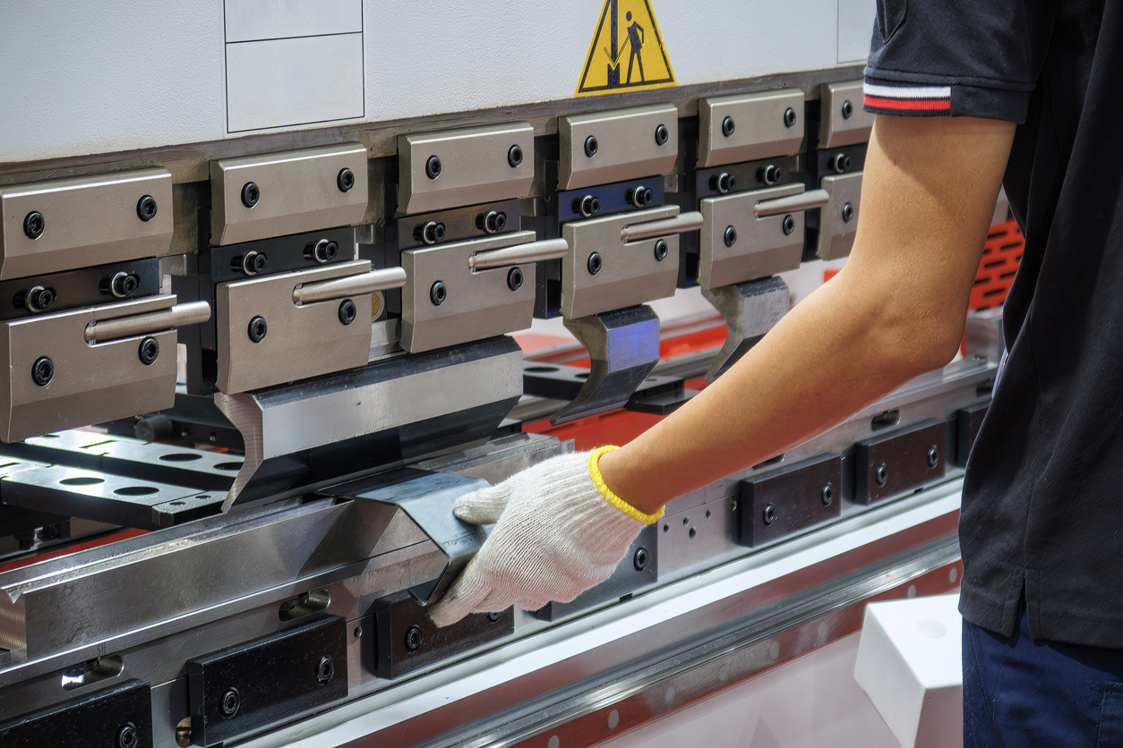 Cierre el operador de la máquina dobladora de prensas plegadoras, sostenga las piezas de chapa con un guante de seguridad.