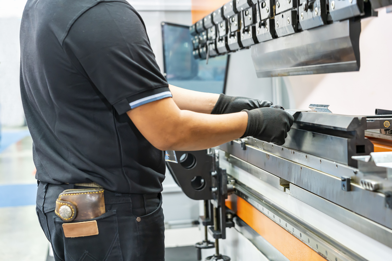 Cierre los dientes de la dobladora hidráulica semiautomática y las manos del técnico atrapan la lámina de metal