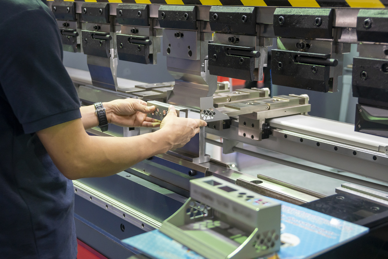 Cierre el operador de la máquina dobladora de prensas plegadoras, sostenga las piezas de chapa con un guante de seguridad