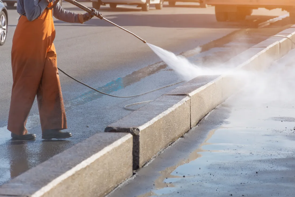 Hombre realizando limpieza de calles utilizando agua tratada