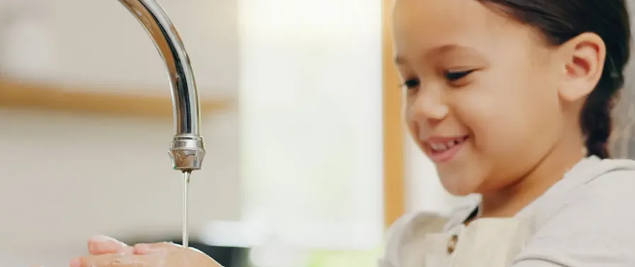 Niña lavándose las manos. Debemos hacer un uso responsable del agua