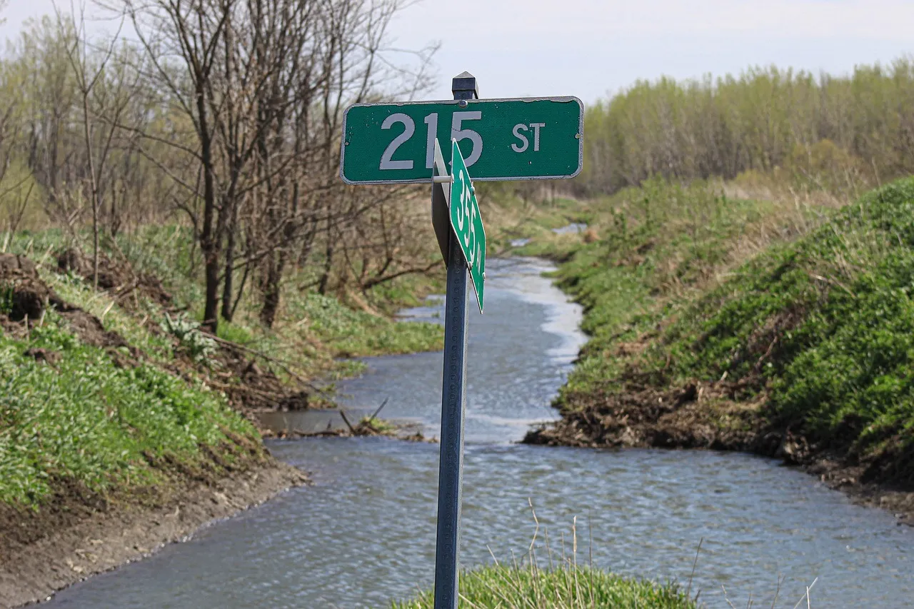 Al frente de una señalización de una carretera y al fondo un rio. Preservar nuestros rios es esencial para el ser humano