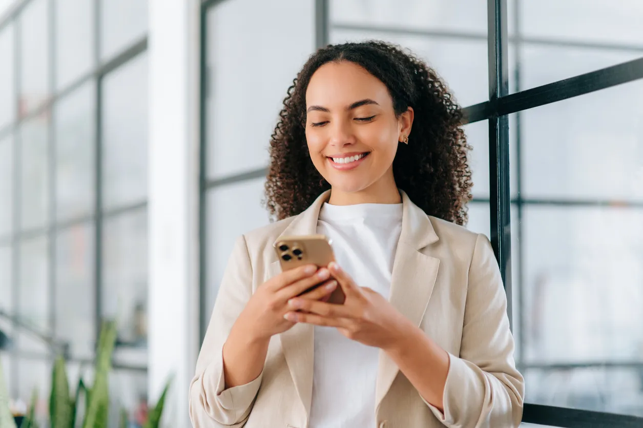 Mujer sonriendo revisando su celular de alta gama