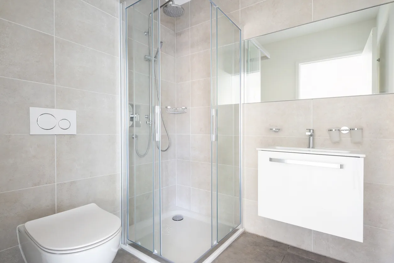 Baño moderno y minimalista con azulejos grandes y ducha. No hay nadie dentro. Baño flotante, gabinete de baño