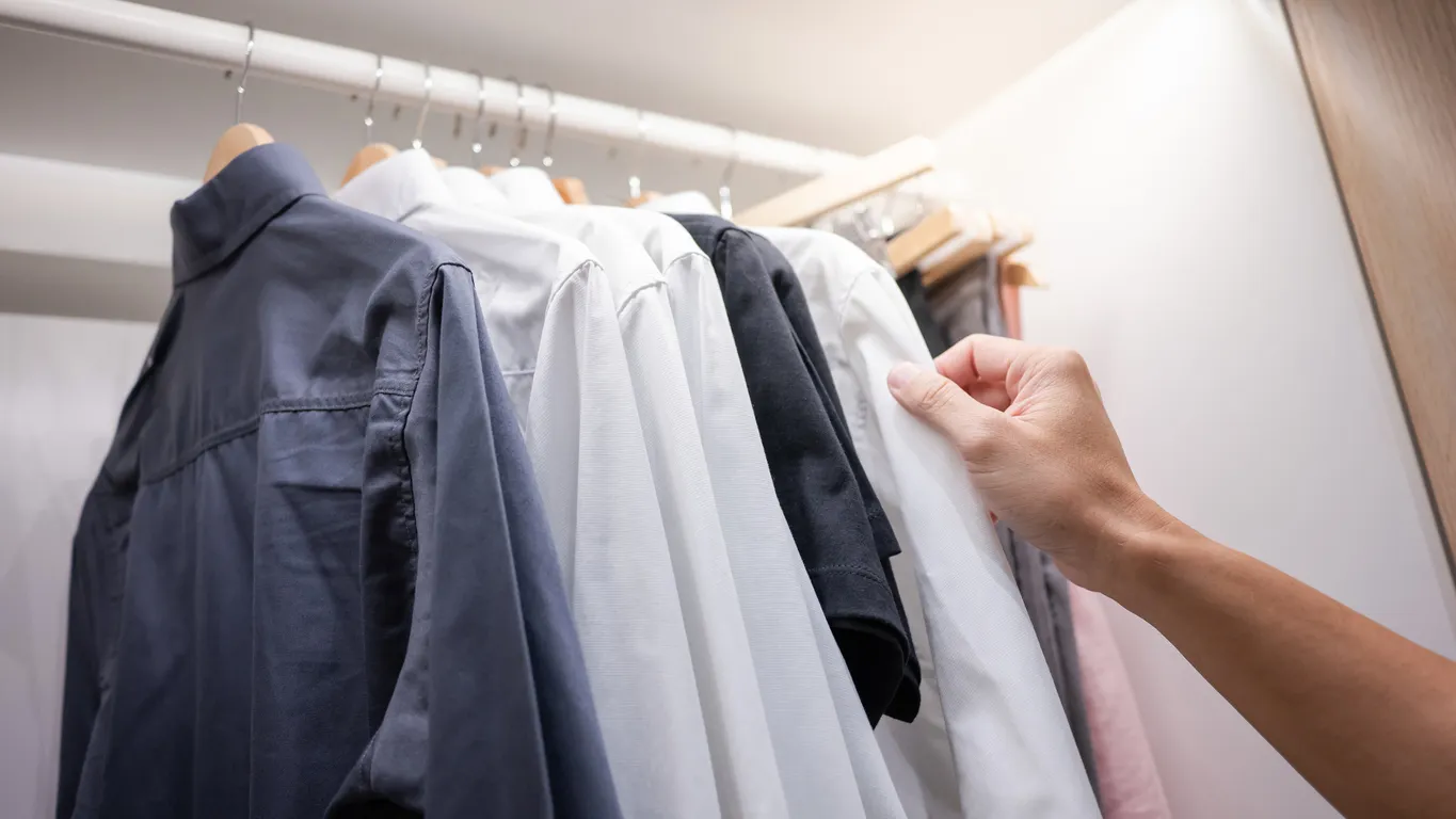 Mano masculina eligiendo camisa, opciones en camisas corporativas.