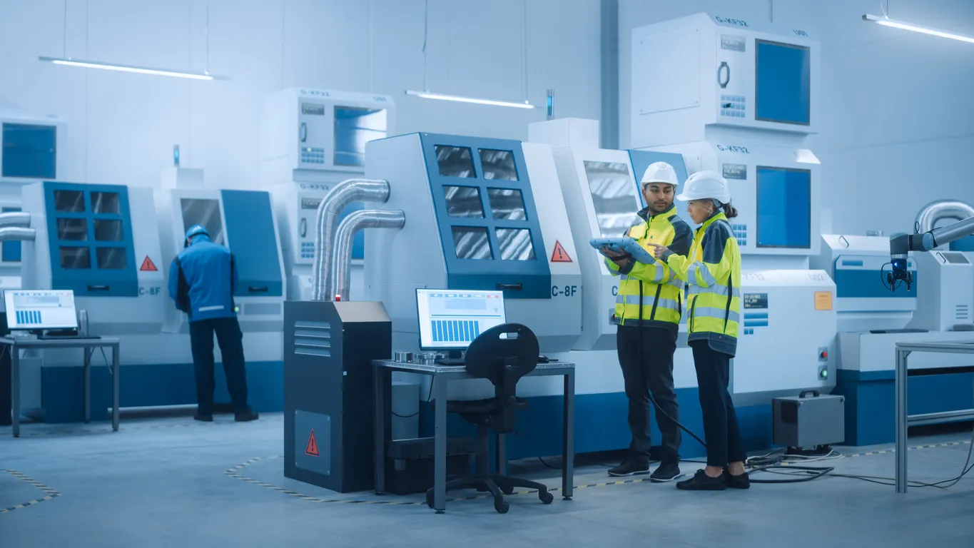 Ingeniero jefe y gerente de proyecto, optimizan la programación de máquinas CNC para aumentar la eficiencia.