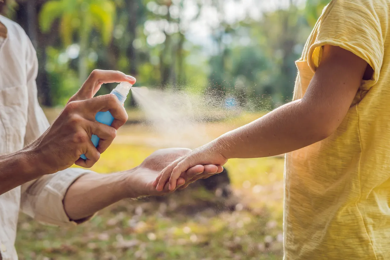 Vista de cerca de la mujer sosteniendo a mano y utilizando repelente de mosquitos a base de aceite esencial casero al aire 