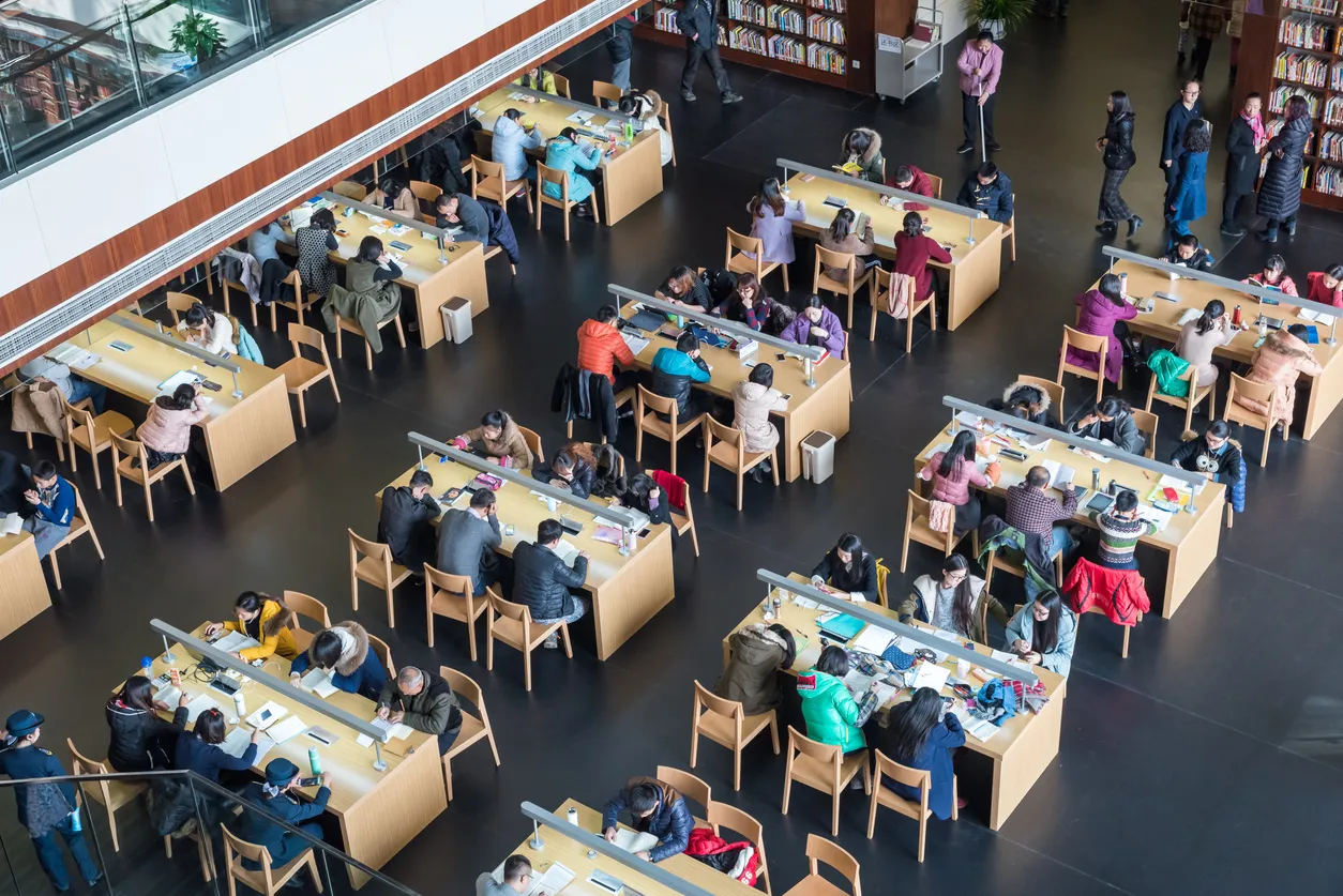 Una gran biblioteca con una gran cantidad de alumnos sentados alrrededor de mesas.Los air cooler climatizan estos lugares.