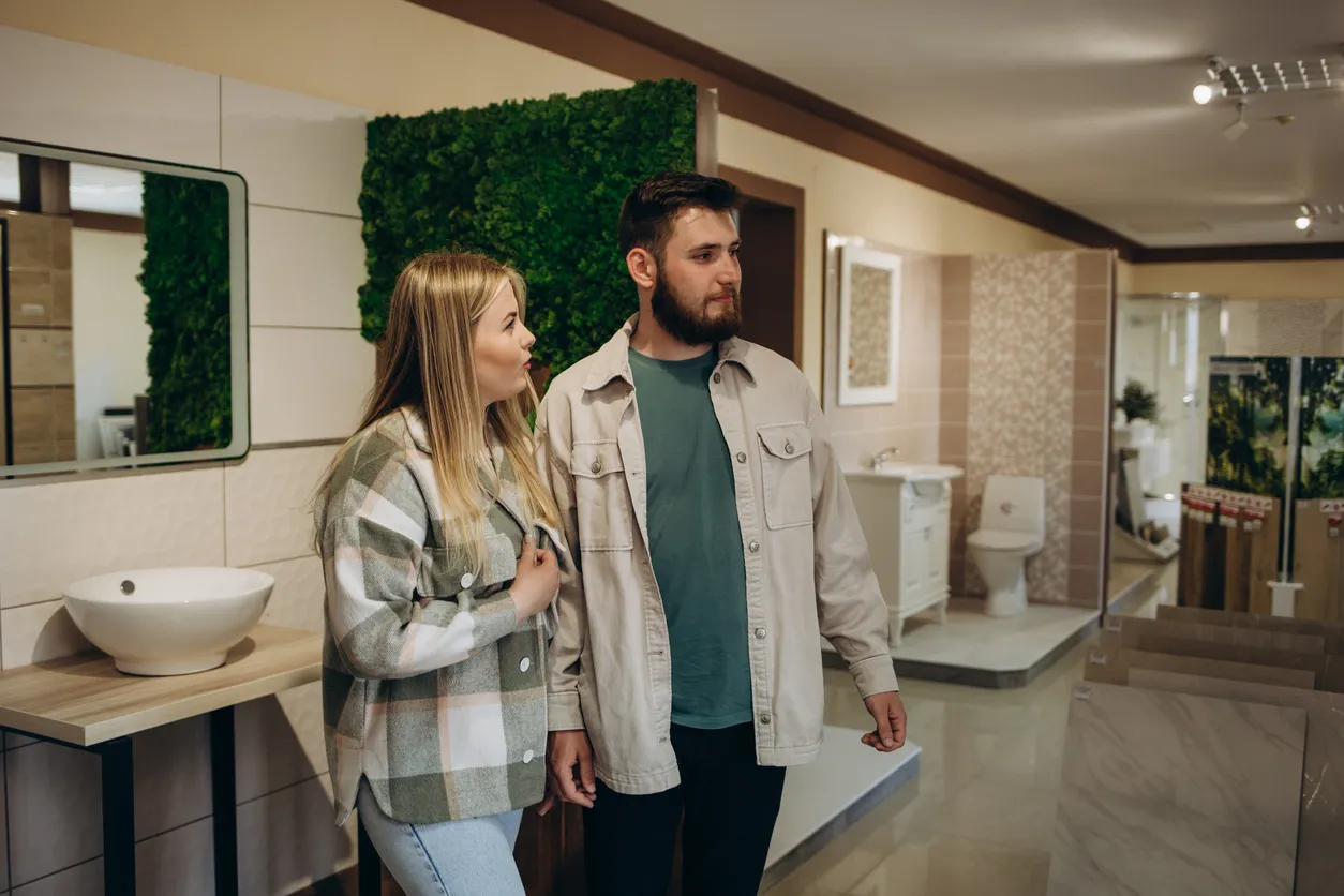 Hombre y mujer en showroom de muebles para baño eligiendo los modelos para vender en su negocio