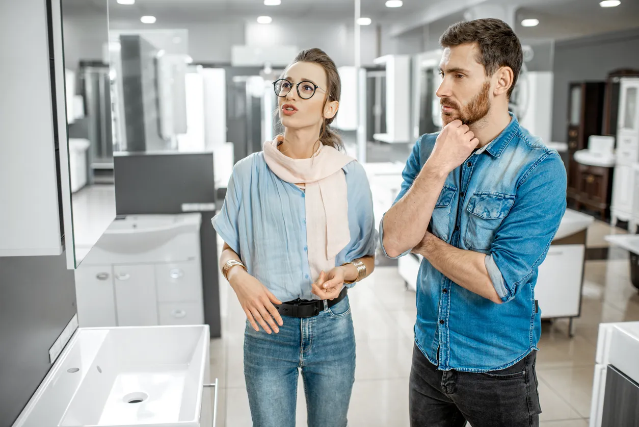 Personas revisando opciones en una tienda de muebles para baño para su negocio. 