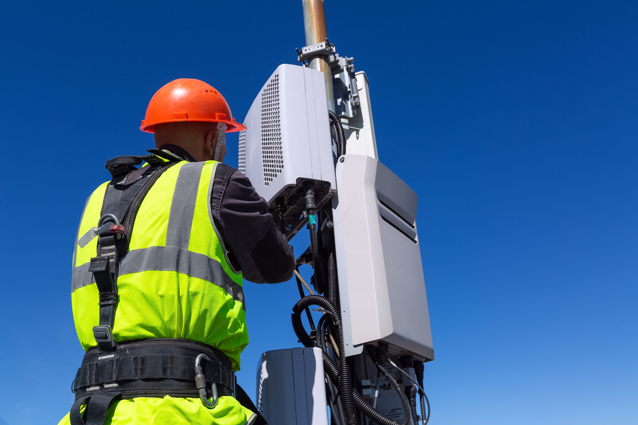 Ingeniero de telecomunicación en casco y uniforme instala equipo de telecomunicación en su mano 