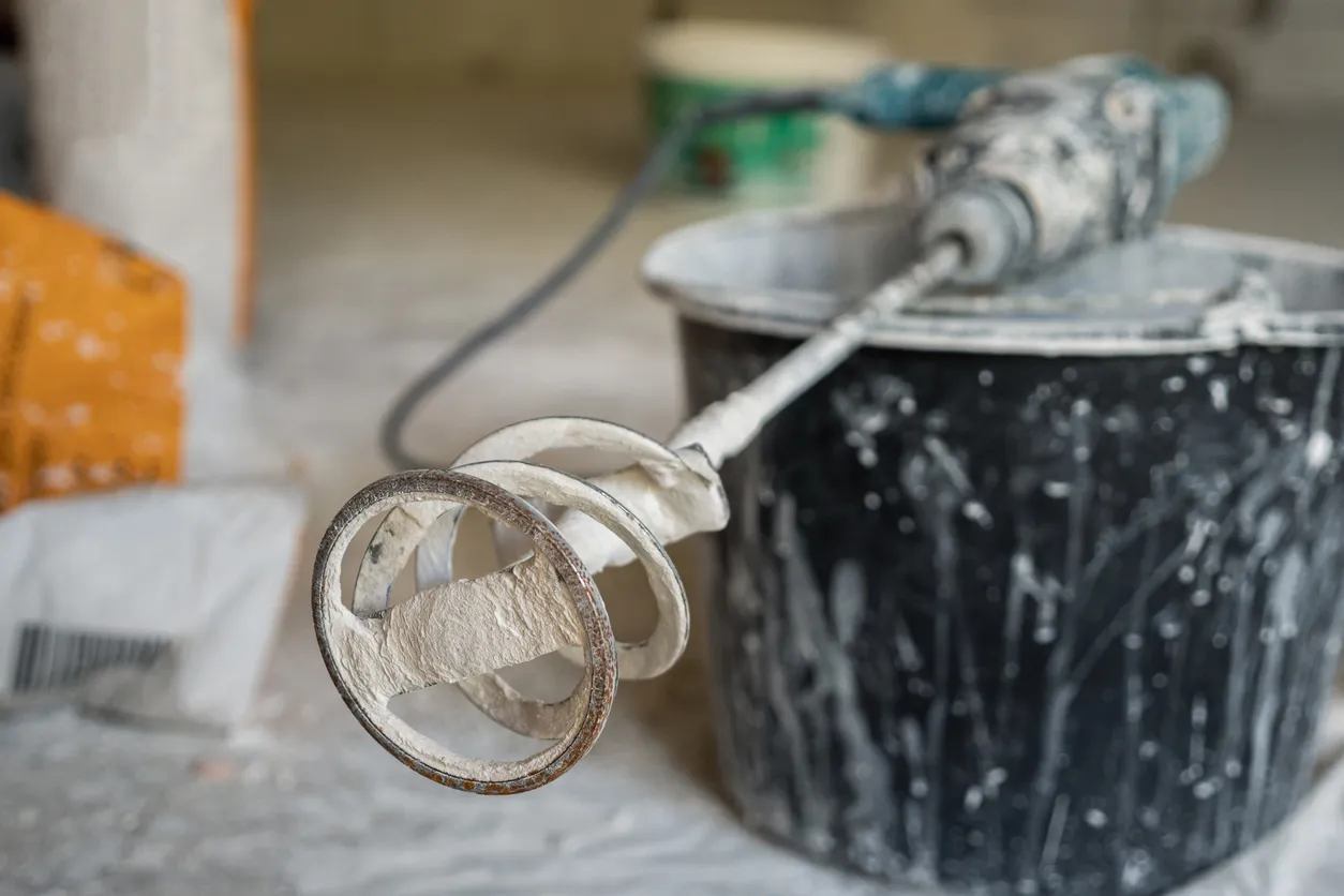 En el cubo de plástico negro hay una herramienta de perforación con un accesorio para mezclar mezclas secas 