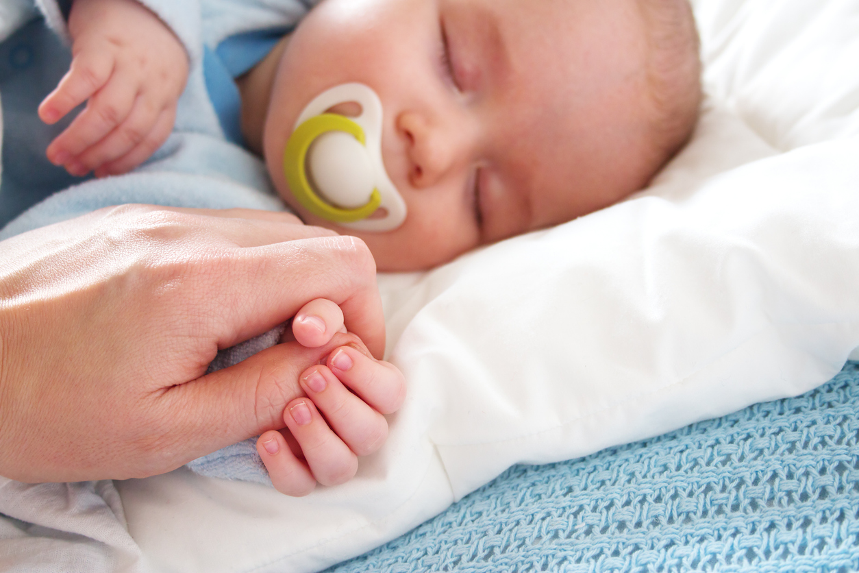 Lindo bebé durmiendo sosteniendo la mano del padre