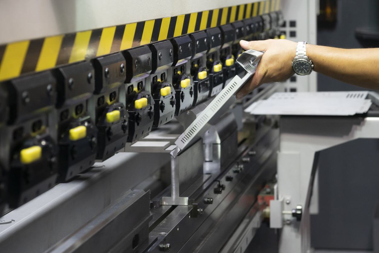 La máquina dobladora funciona con placas de metal pesado en el taller