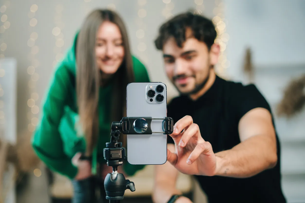 pareja de personas preparando un celular en un tripie para realizar una foto o video