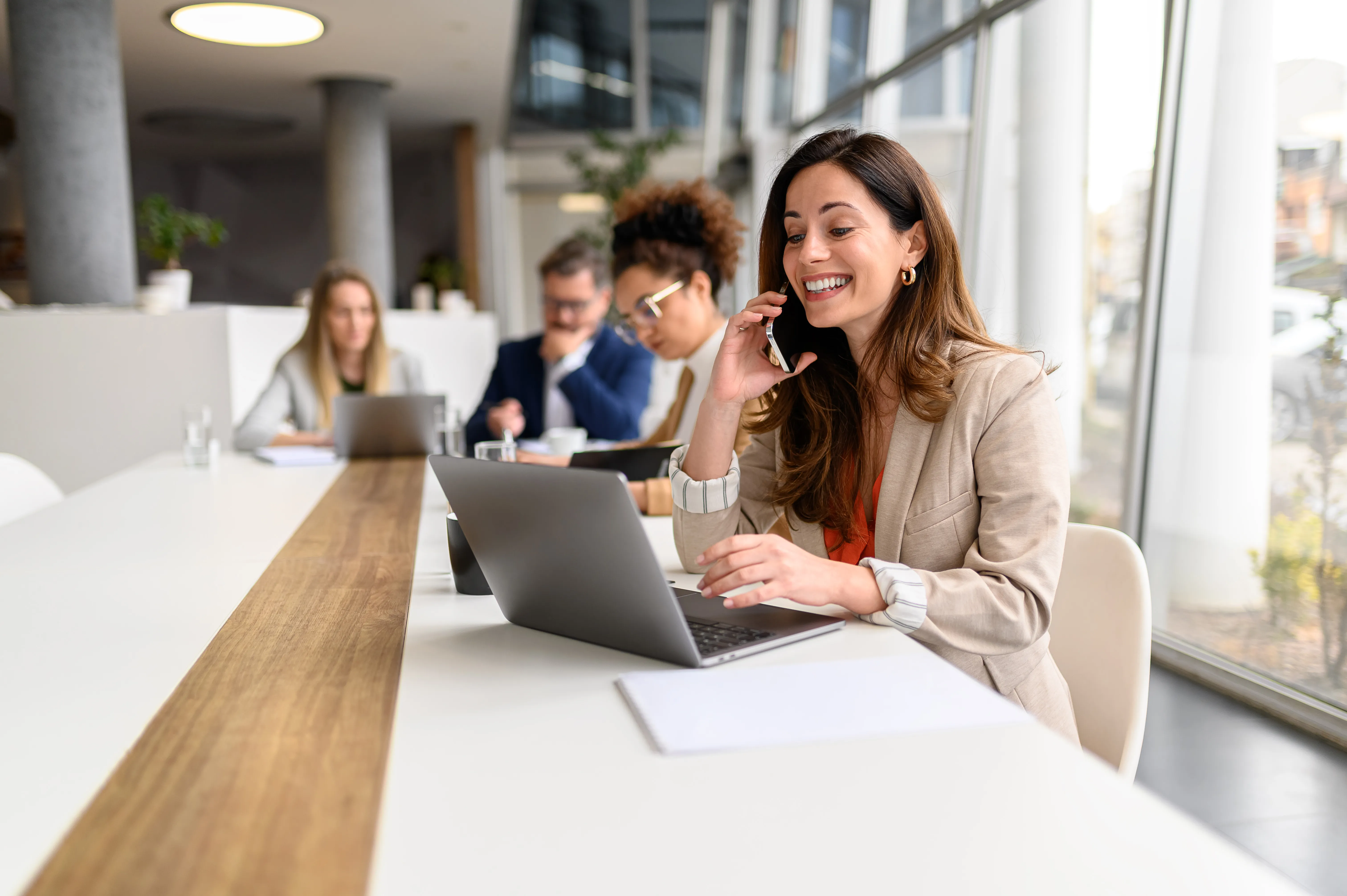 Profesional femenina feliz hablando por celular SAMSUNG alta gama mientras trabaja en una sala de juntas