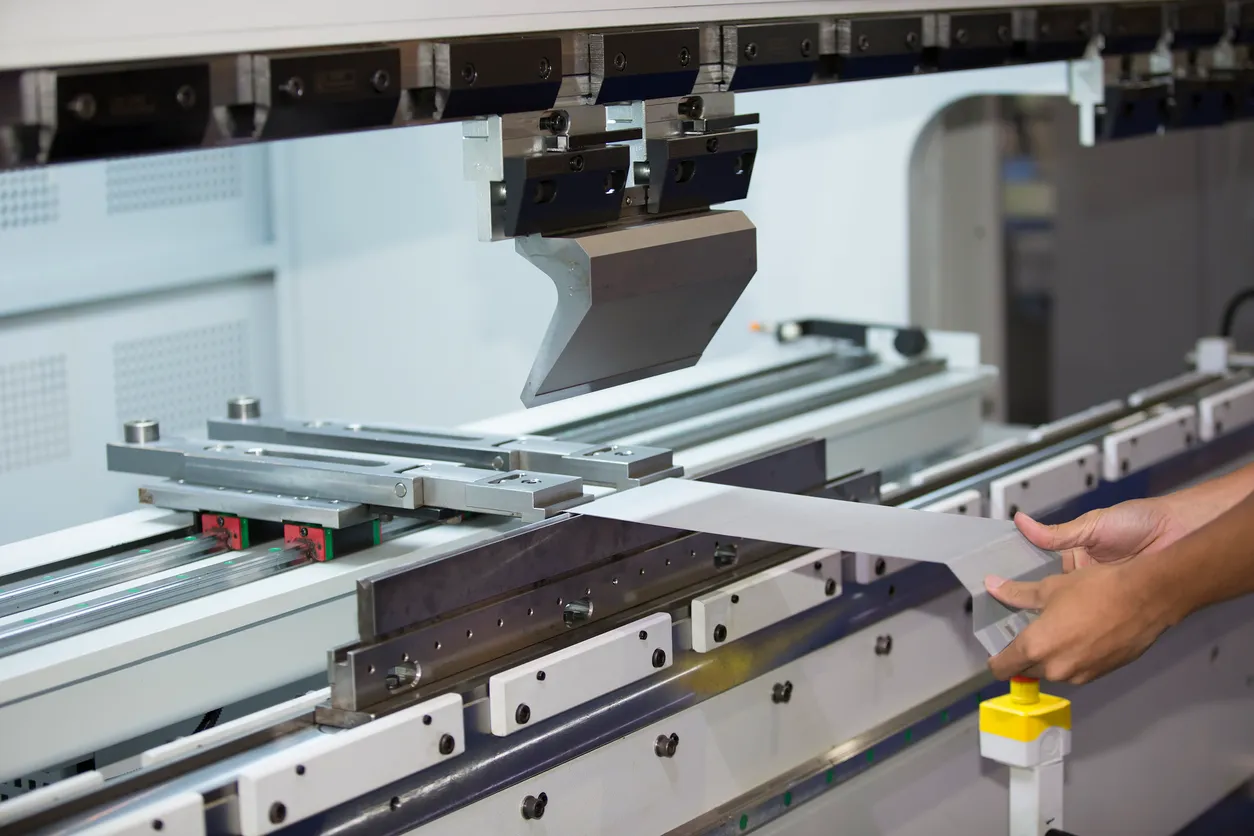 Operador doblando chapa metálica con máquina dobladora de chapa