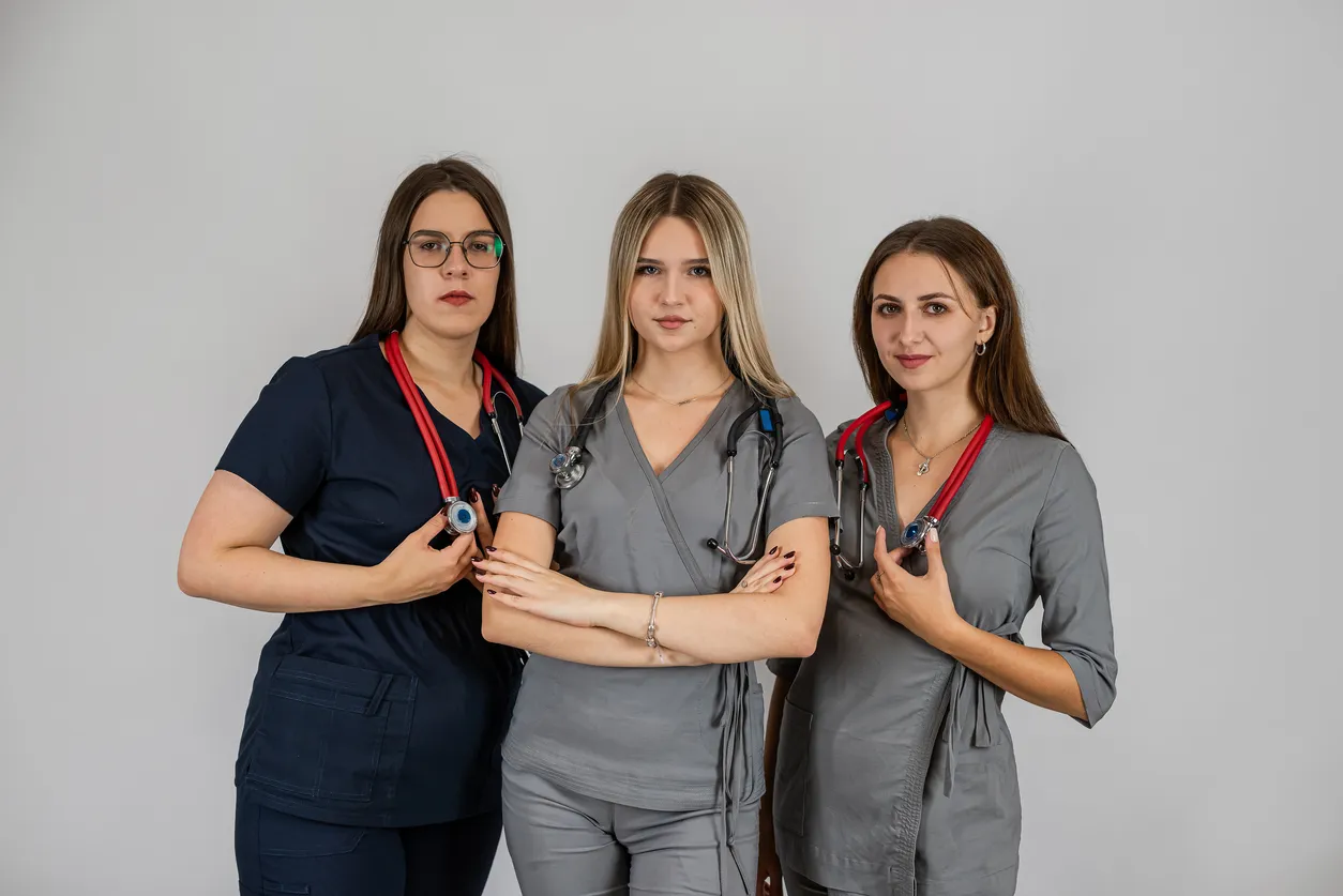 Tres jovenes enfermeras con scrubs medicos en color gris y negro
