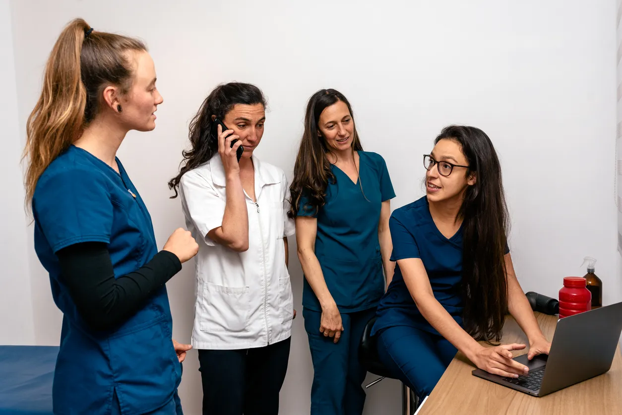 Varaias enfermeras y doctoras con scrubs médicos reunidas en un consultorío